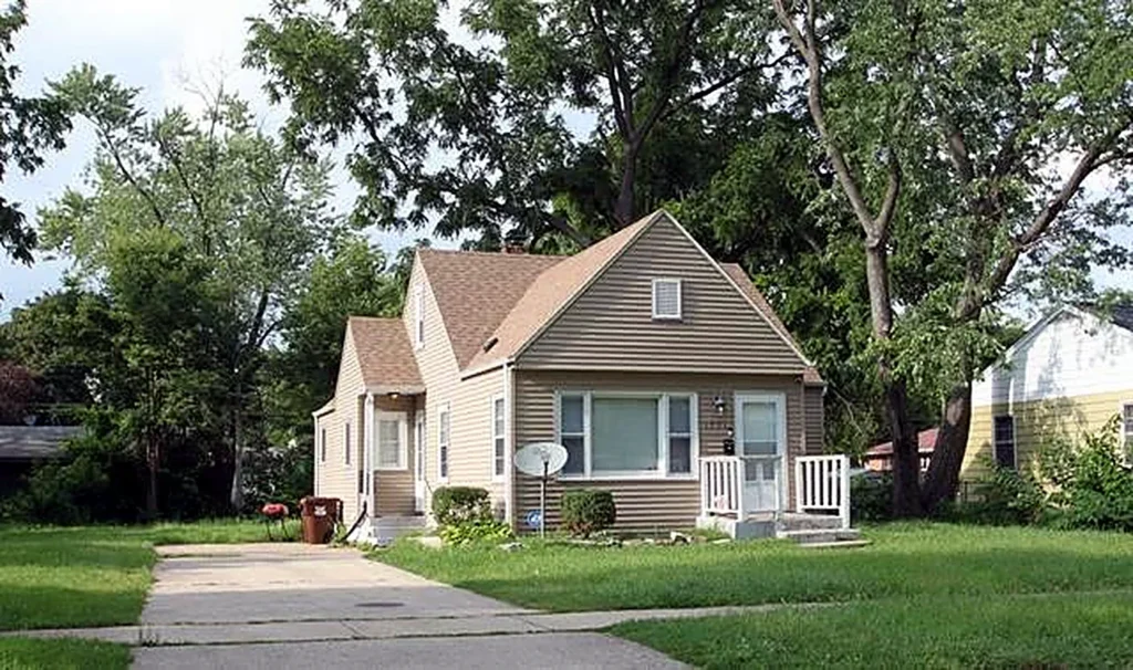 Cape Cod style home with a long driveway and shade trees