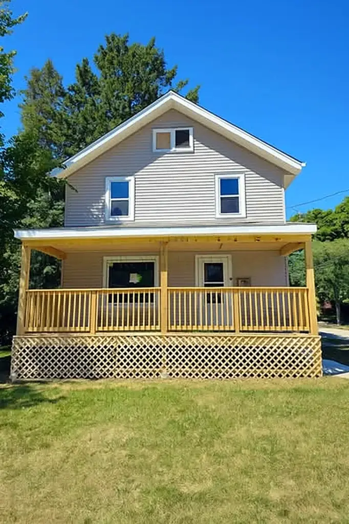 Two-story home with a new wood front porch and lattice skirting